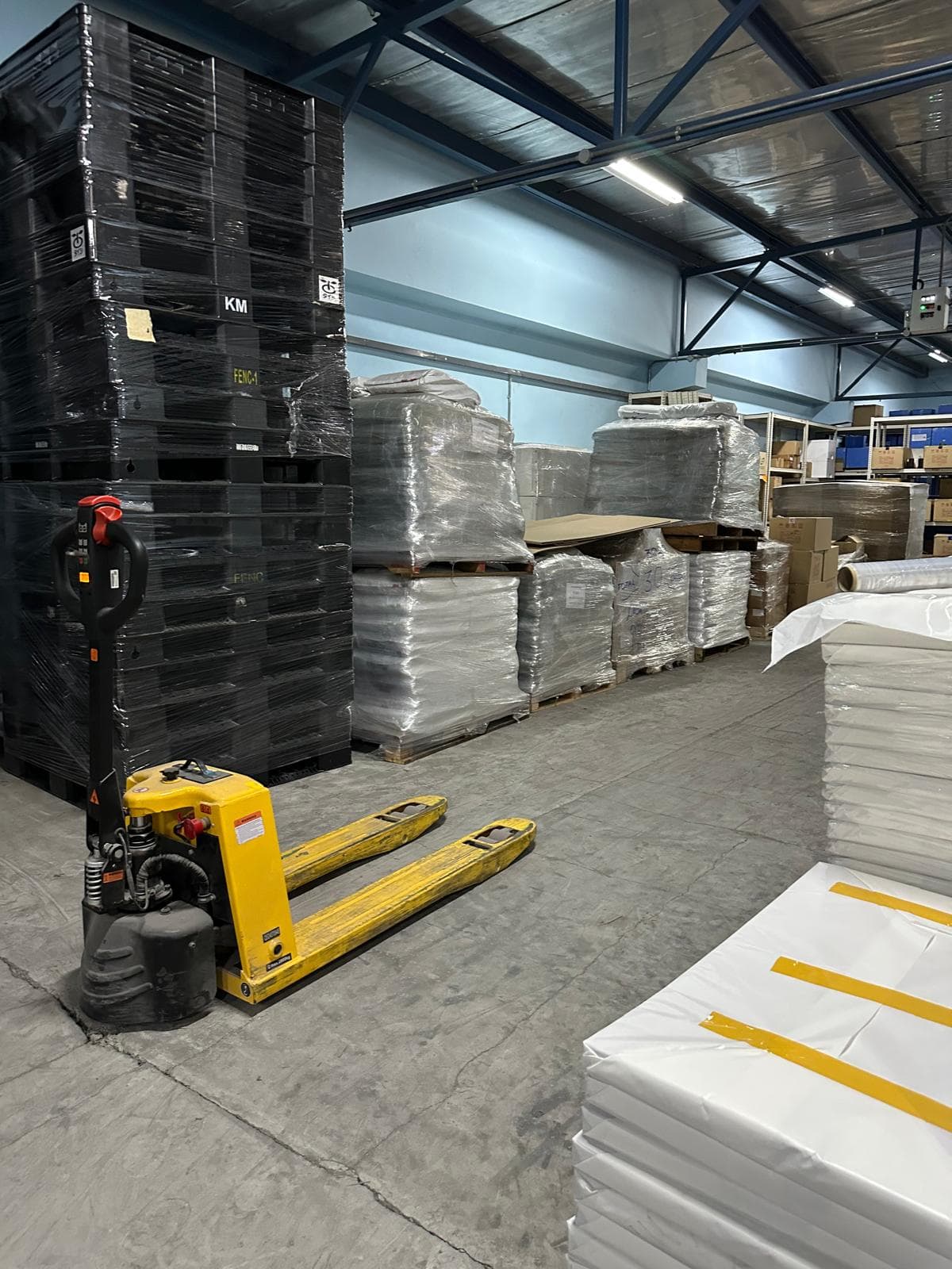 Megapac warehouse — stacked returnable pallets and wrapped stock with electric pallet jack